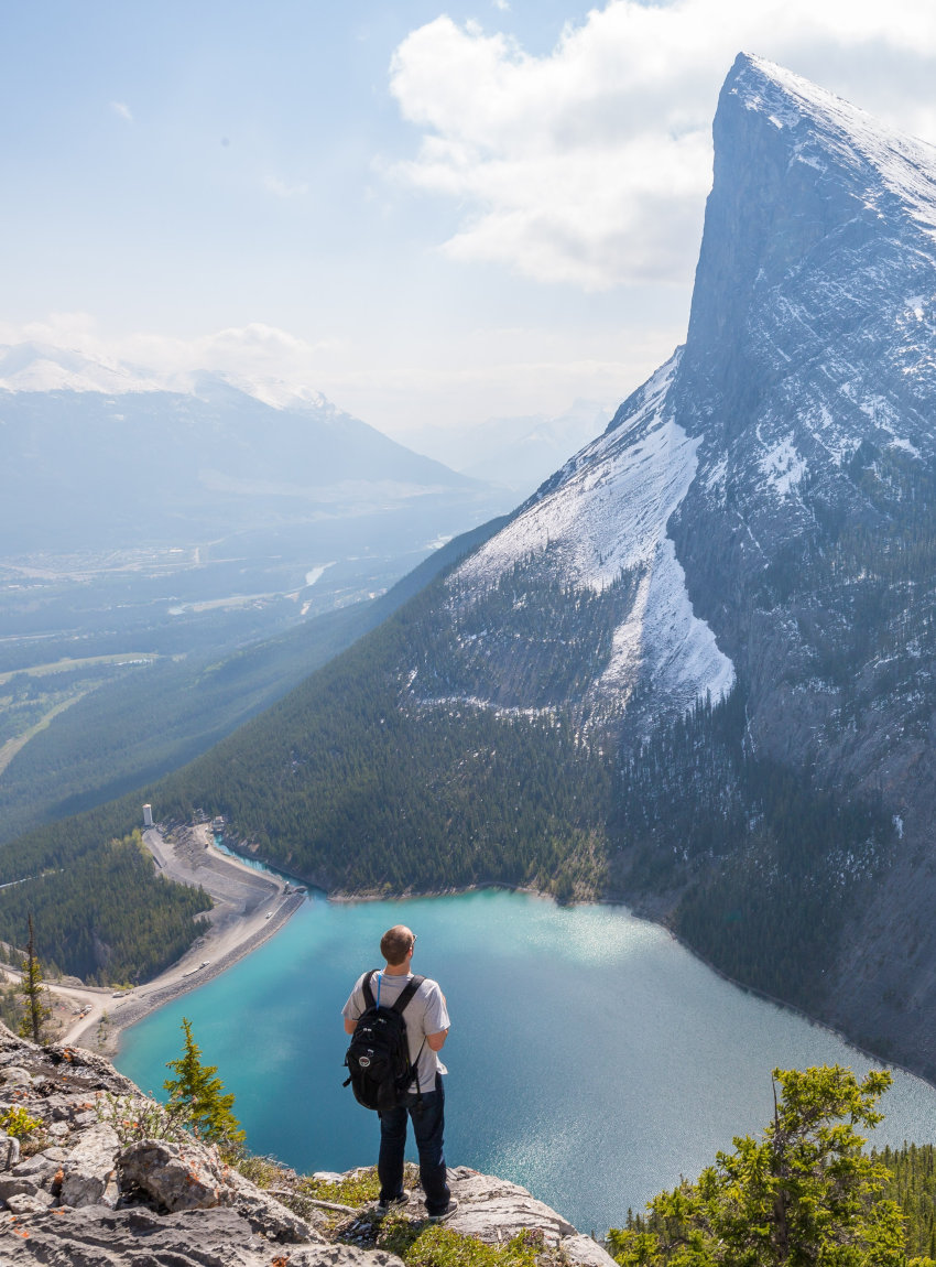 Ein Mann steht am Ende des East End Rundle Trails in Kanada und blickt auf einen wundervollen See am Fuße eines Berges